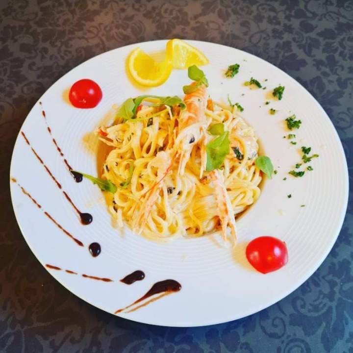 Spaghettis aux crevettes et tomates cerises, servis avec de la roquette et une sauce blanche Arras