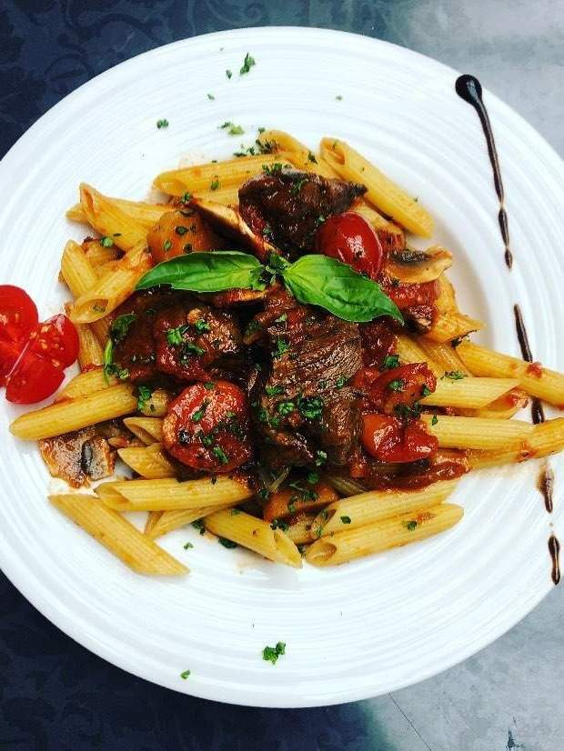 Pâtes penne servi avec un sauté de veau, chorizo et olives dans une sauce tomate Arras